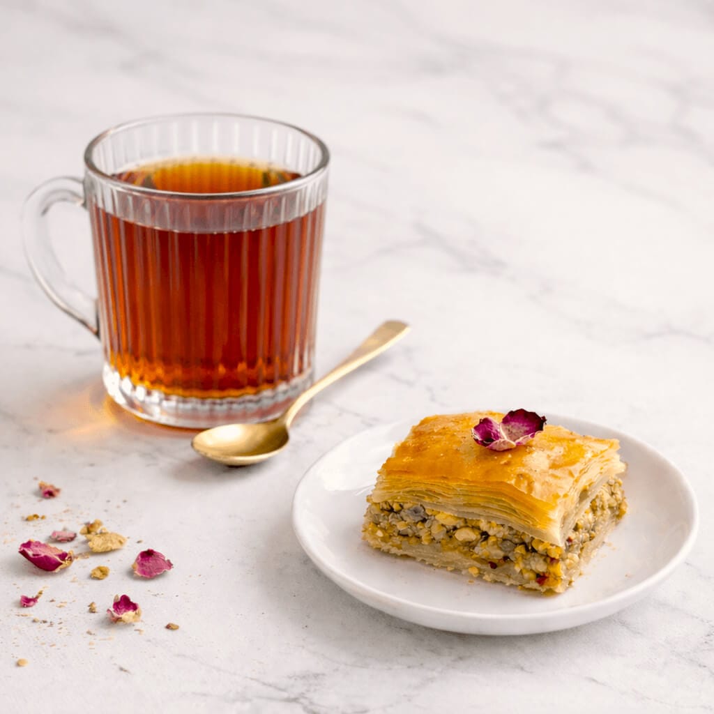 A piece of homemade almond and pistachio baklava served with tea.