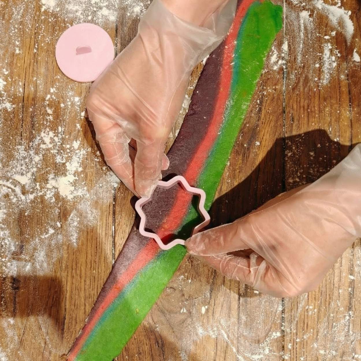 Cutting layered rainbow cookie dough using a Ramadan-shaped cookie cutter on a floured surface