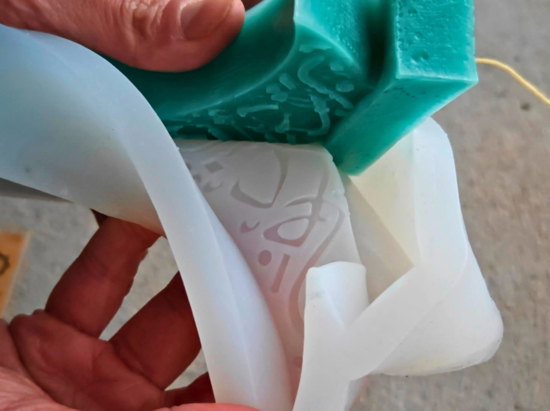 Removing a set beeswax Ramadan candle from a flexible silicone mold after 24 hours, showing clean architectural details.