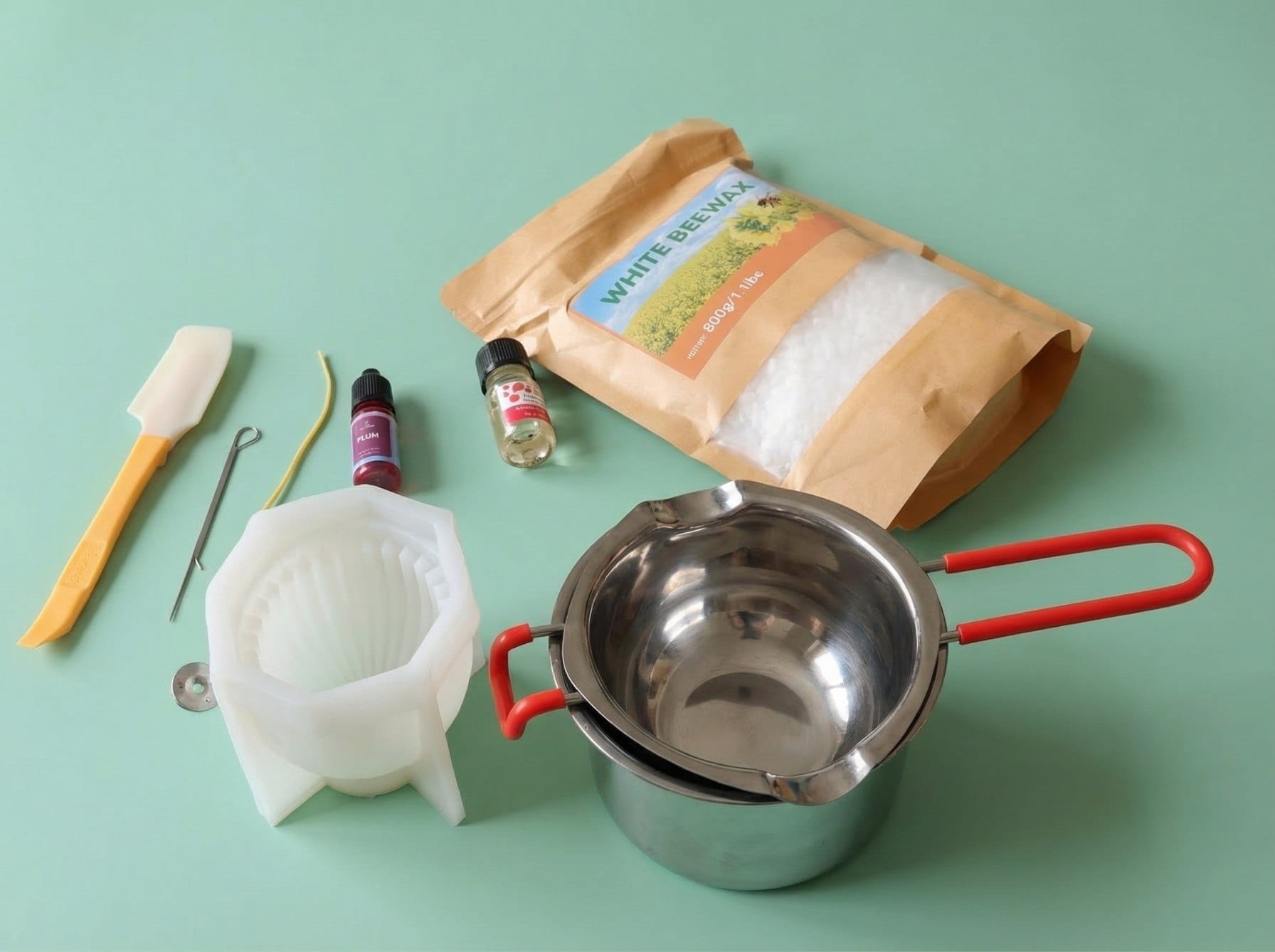 Supplies for DIY Ramadan beeswax candles including silicone mold, natural beeswax pellets, essential oils, wick, and double boiler setup.