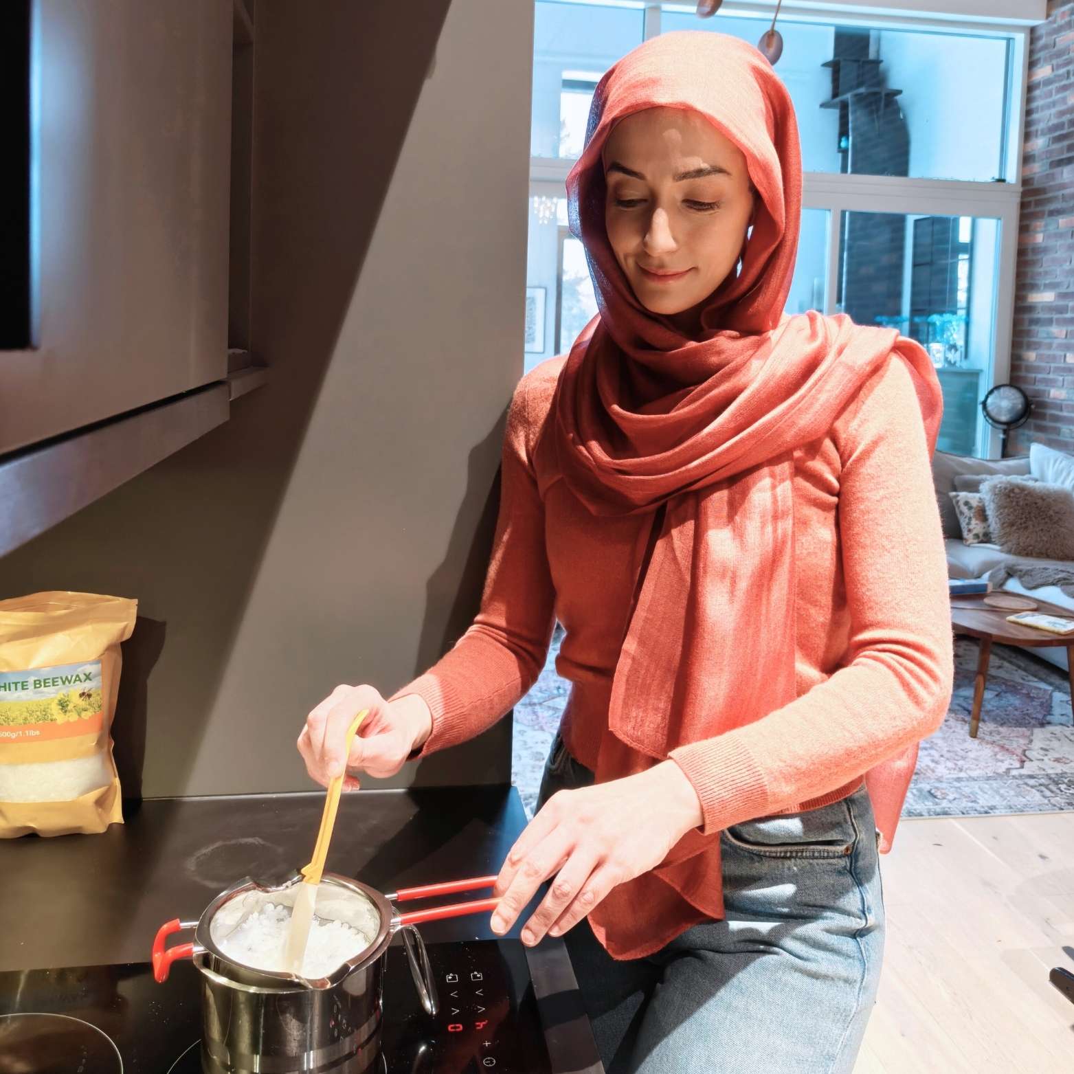 Melting natural beeswax in a double boiler on the stovetop while stirring gently to prepare DIY Ramadan candles.