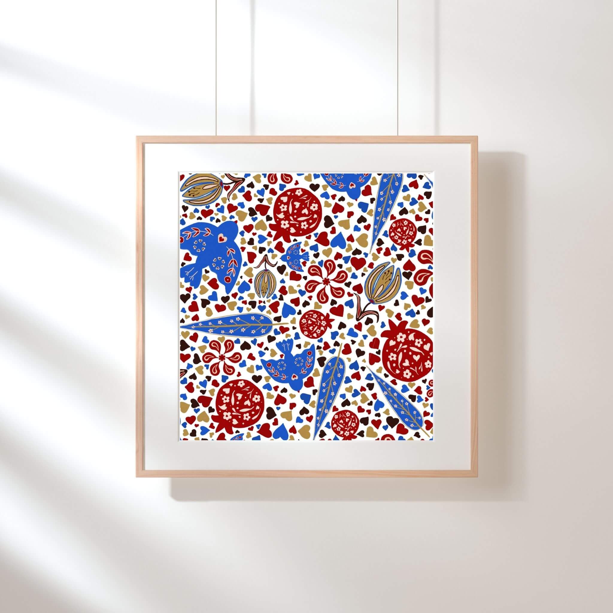 Persian pomegranate art print featuring red pomegranates, blue birds, tulip motifs and scattered heart shapes in a detailed Islamic-inspired pattern, framed in light wood on a neutral wall.