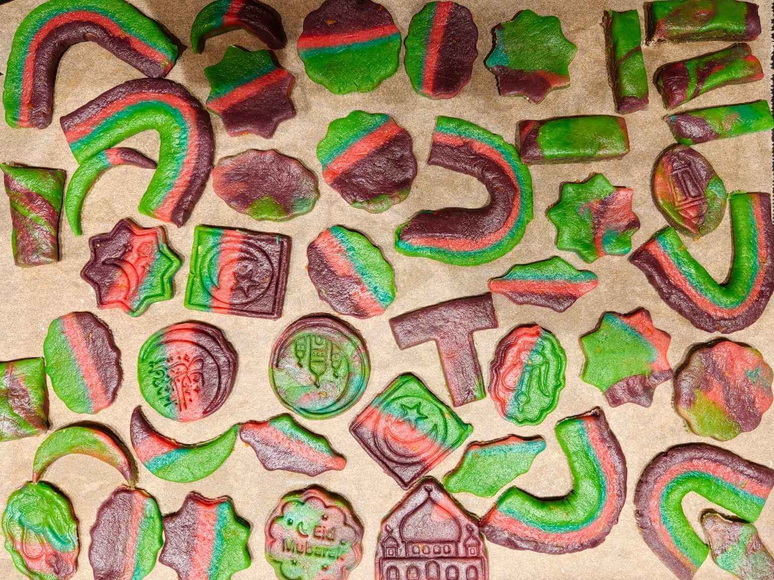 Rainbow Ramadan butter cookies in mixed shapes and colours arranged on a lined baking tray before baking