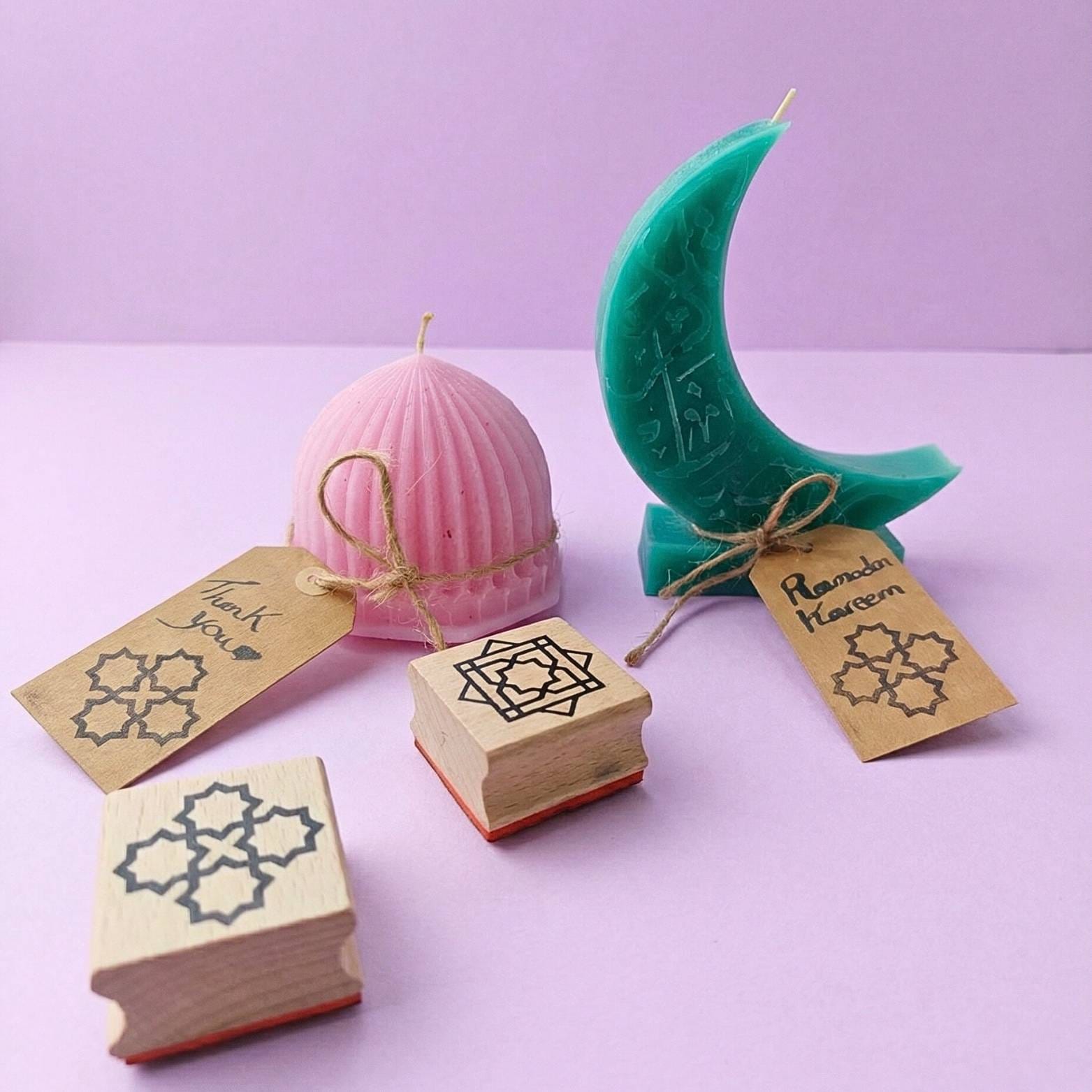 Pastel beeswax Ramadan candles wrapped with twine and kraft gift tags stamped with Islamic geometric patterns using a wooden stamp.