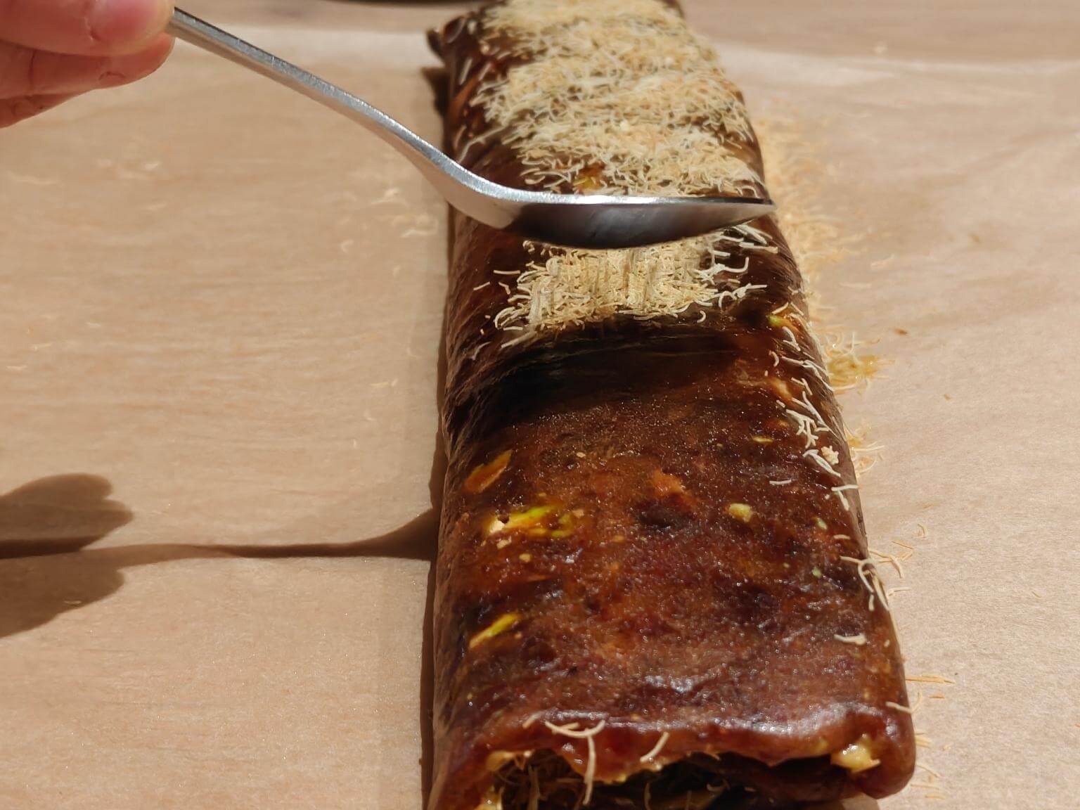 pressing crispy kataifi onto the outside of a pistachio date dessert log