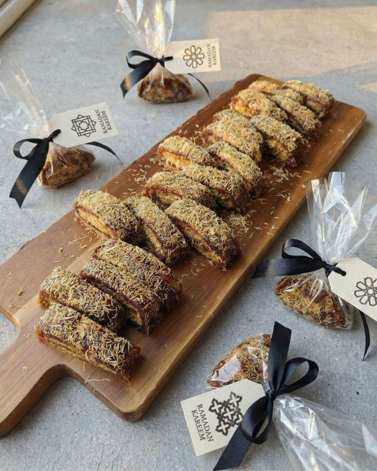sliced no bake date dessert with pistachio and kataifi served on wooden board with Ramadan gift packaging