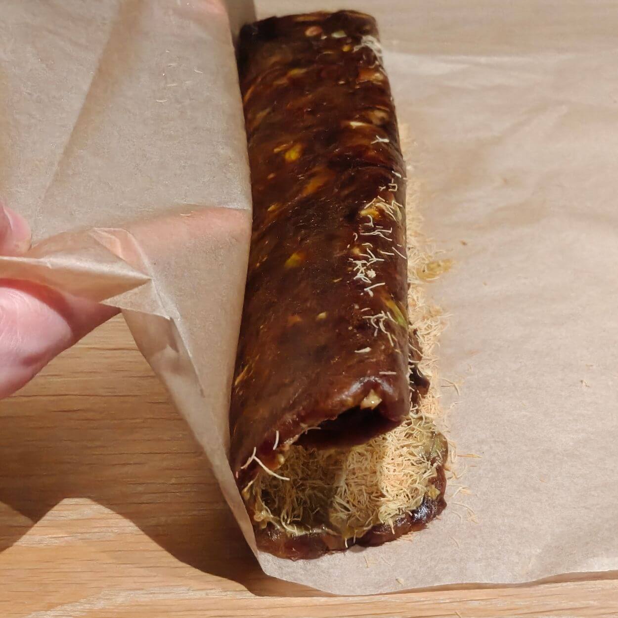 rolling no bake date dessert log using baking paper with pistachio and kataifi