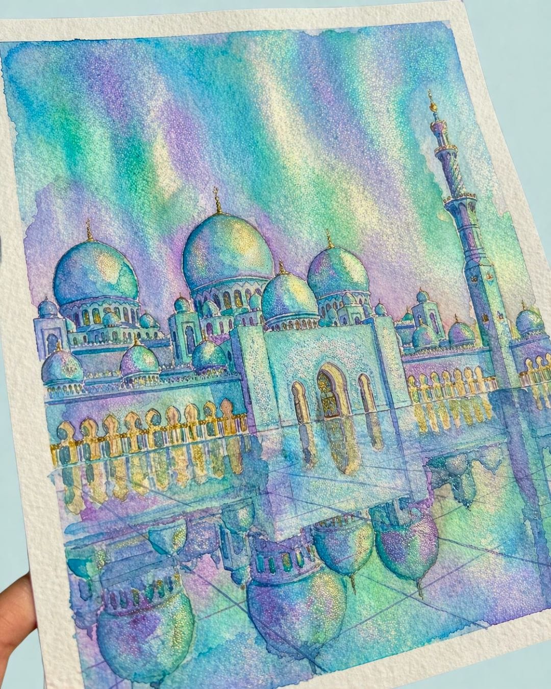 Shimmering watercolor mosque painting in turquoise, blue, and soft lilac tones with metallic highlights, showing an Islamic-inspired artwork created with pearlescent watercolor paints.