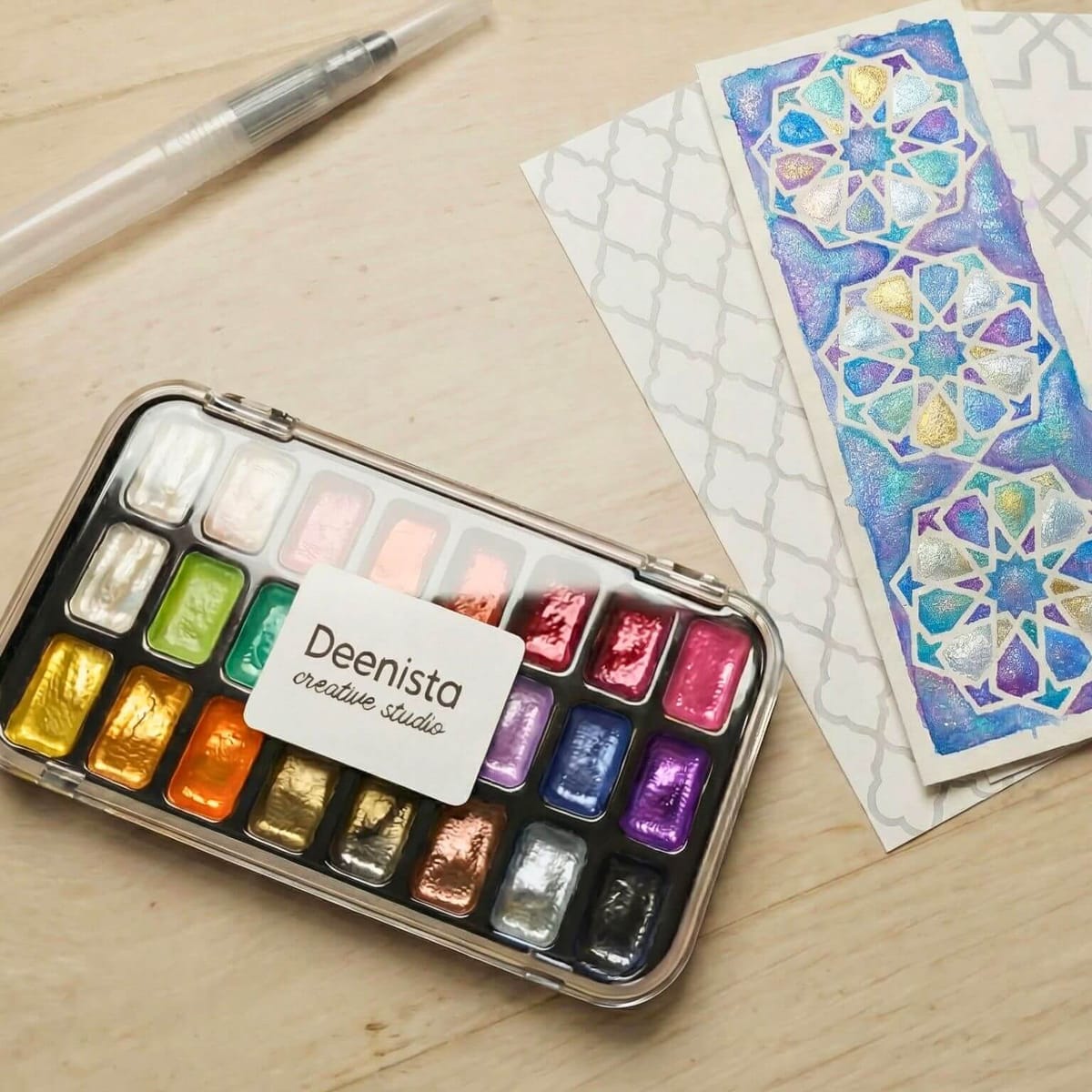Deenista Islamic shimmer watercolor kit with 24 pearlescent paints, refillable water brush, and a finished geometric bookmark design.